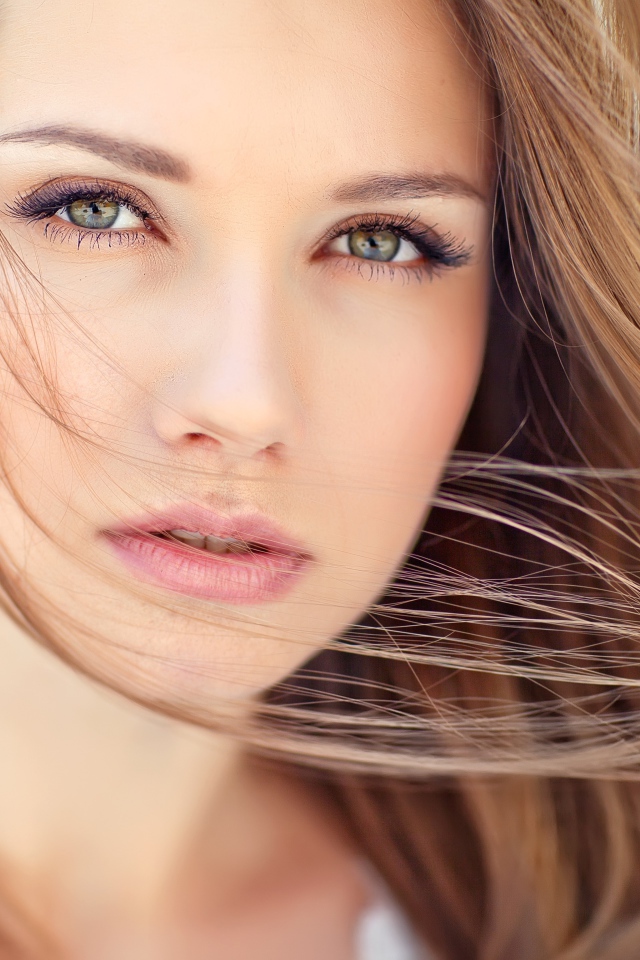 Волосы развеваются ветром на лице у девушки