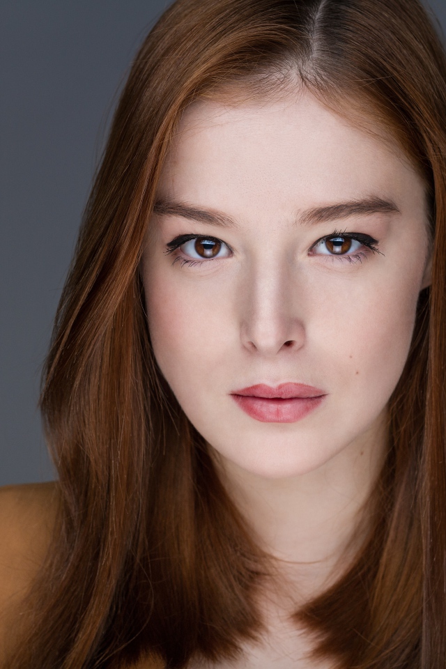 Рыжеволосая  молодая девушка на сером фоне