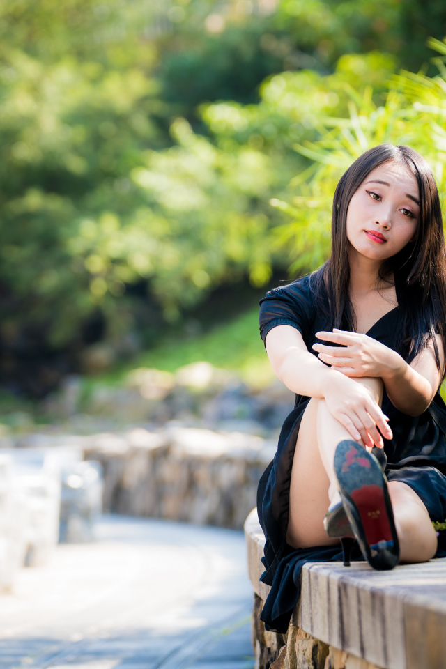 Грустная девушка в черном платье отдыхает в парке