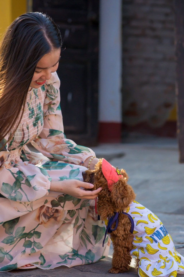 Улыбающаяся девушка азиатка с собакой 