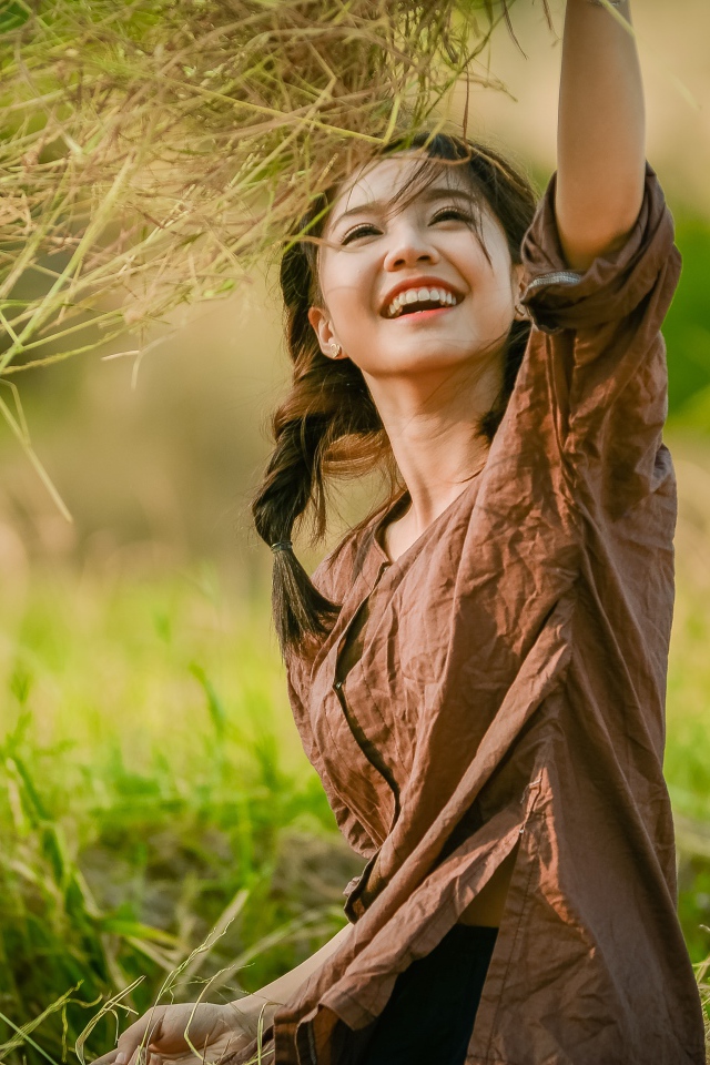 Улыбающаяся девушка азиатка с травой в руках 