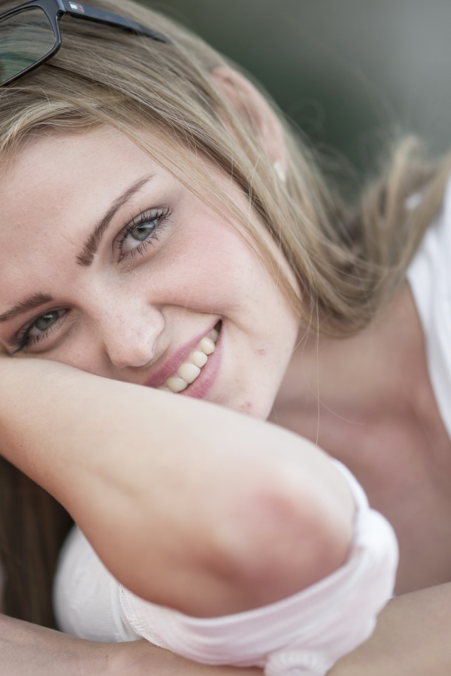 Улыбающаяся девушка блондинка с очками на голове