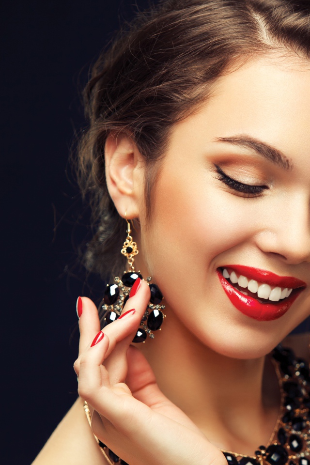 Улыбающаяся девушка носит украшения с черными камнями