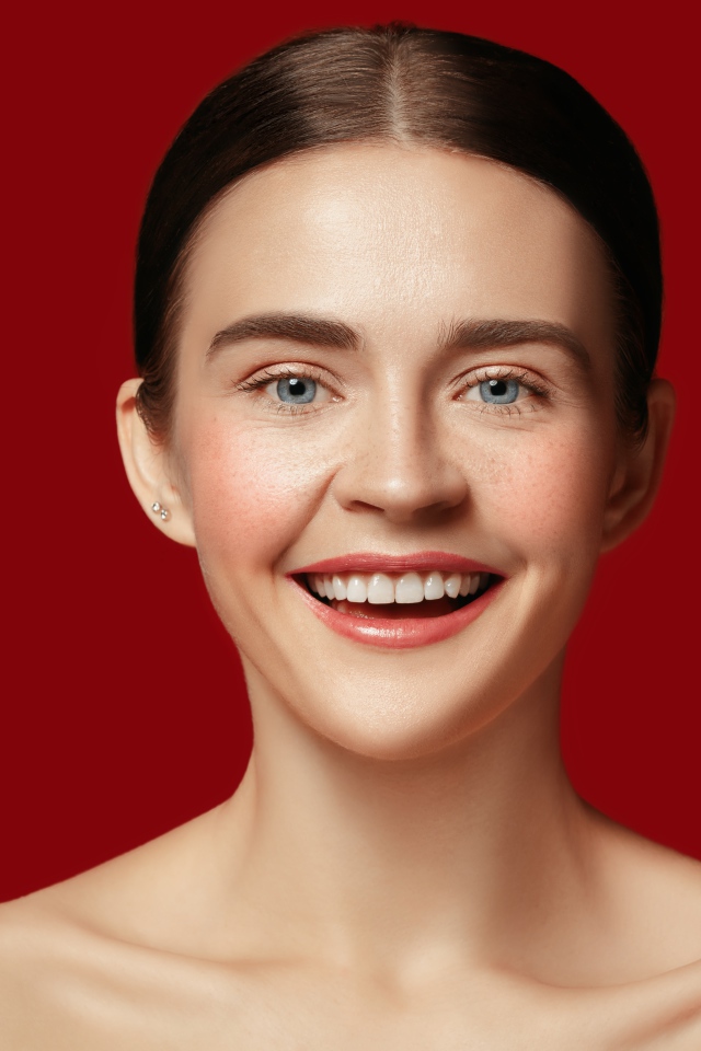 Улыбающаяся молодая девушка на красном фоне