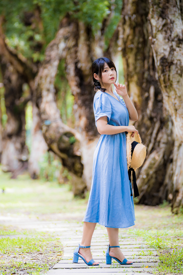 Стильная девушка азиатка в голубом платье в парке 