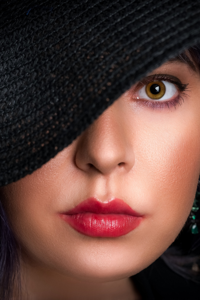 Глаз девушки закрыт черной шляпой 