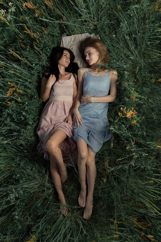 Две девушки лежат в высокой траве