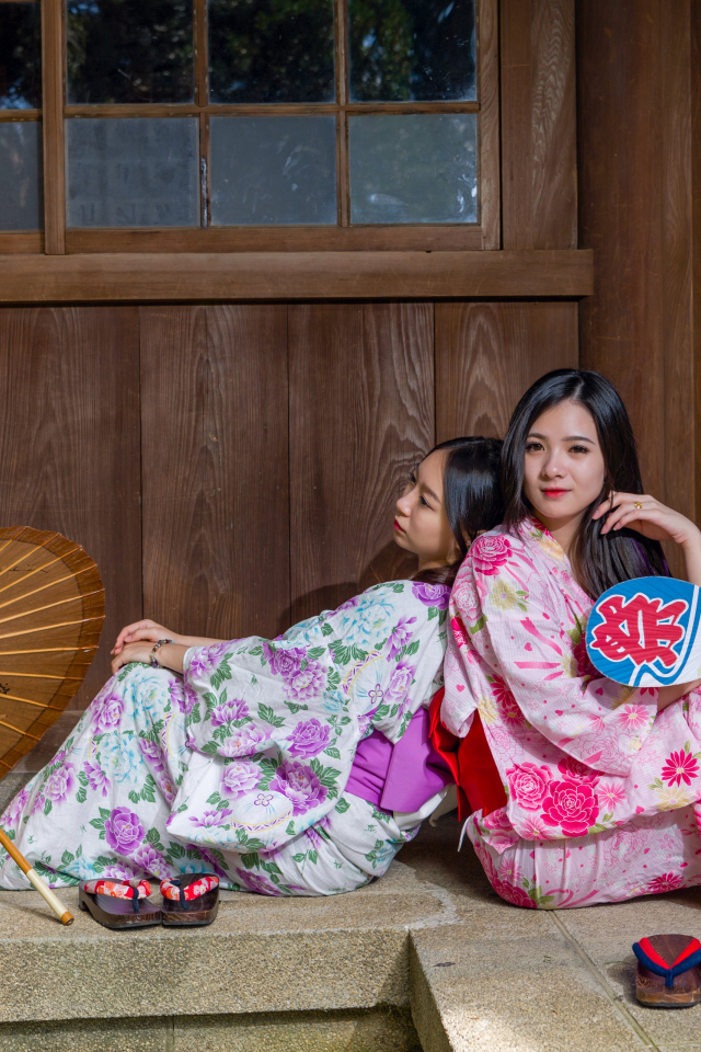 Две молодые девушки в кимоно сидят на полу