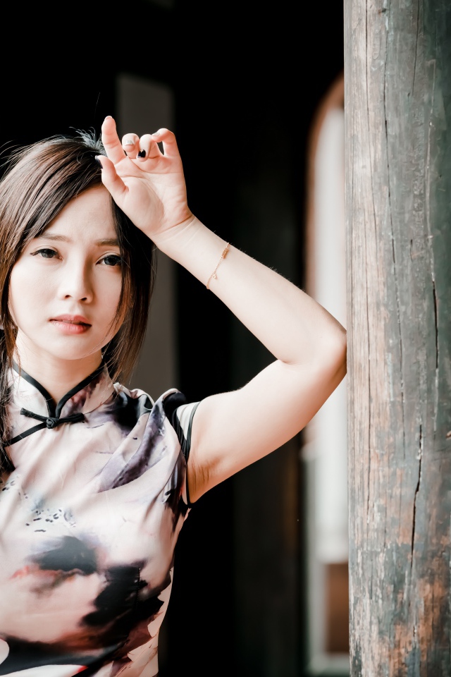 Молодая девушка азиатка стоит у столба 