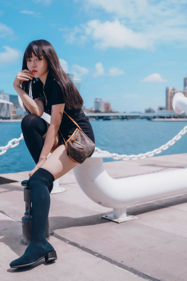 Молодая азиатка сидит в порту 