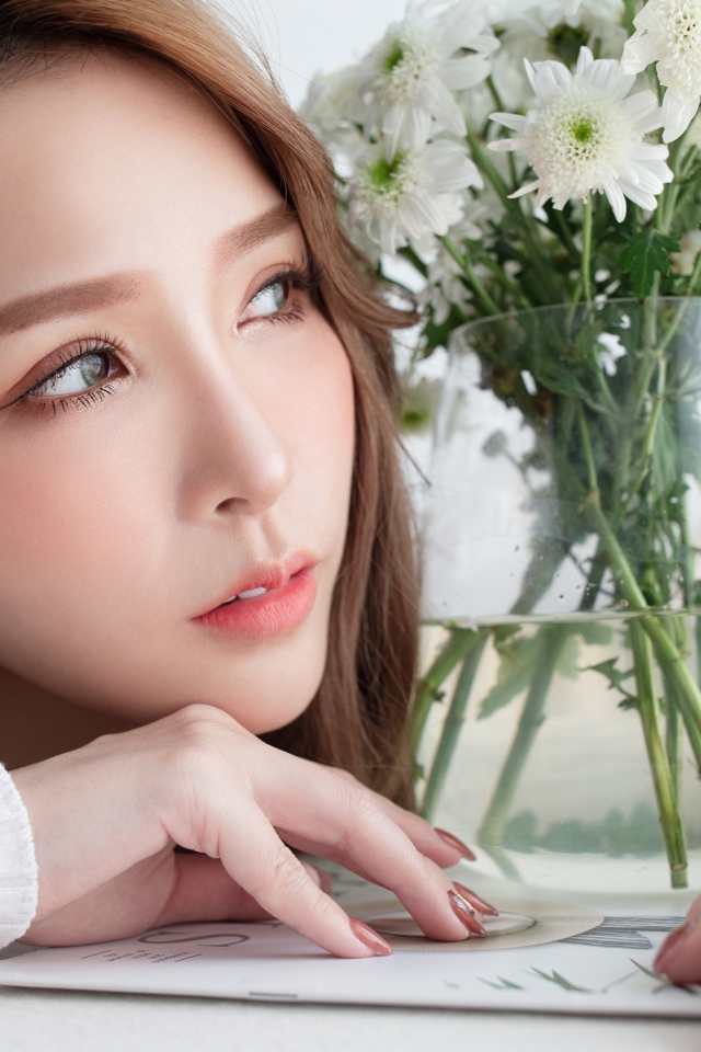 Молодая азиатка с букетом белой хризантемы в вазе