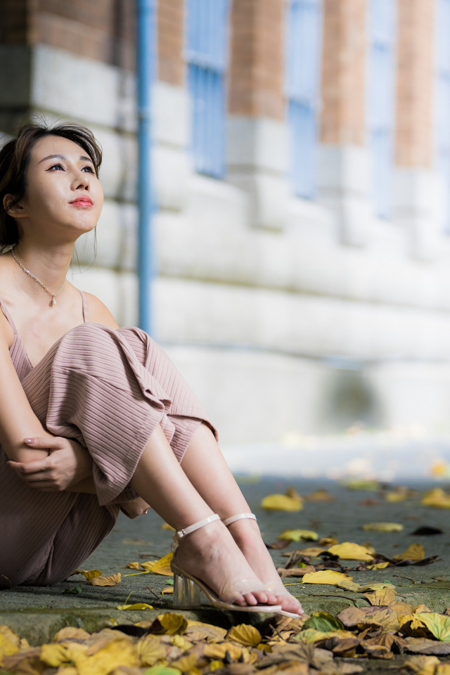 Молодая девушка азиатка сидит на земле с листьями 