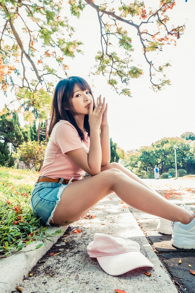 Молодая азиатка сидит на земле в осеннем парке