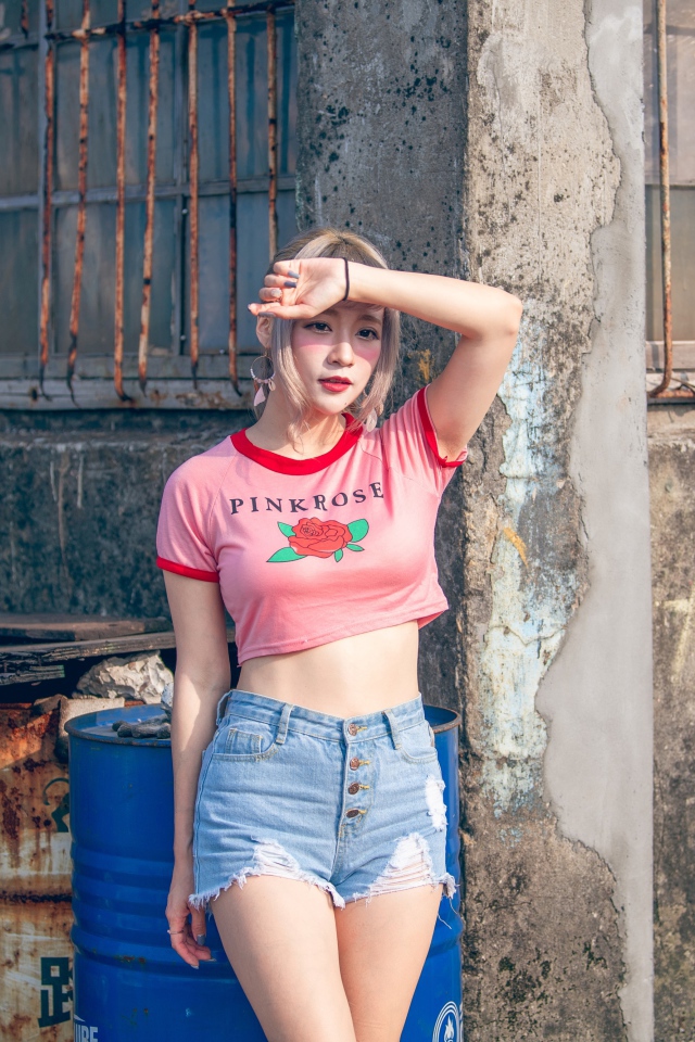 Молодая азиатка стоит у стены 