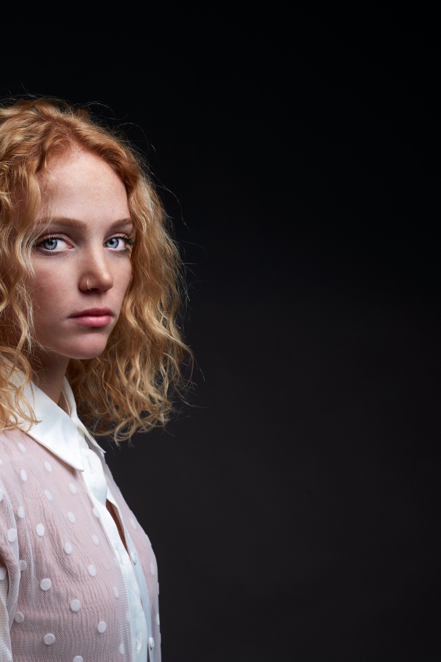 Молодая рыжеволосая девушка на черном фоне