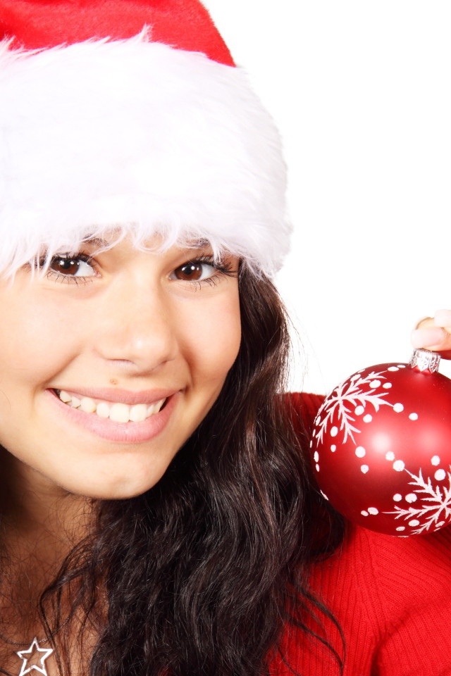 Улыбающаяся девушка с елочной игрушкой в руке 