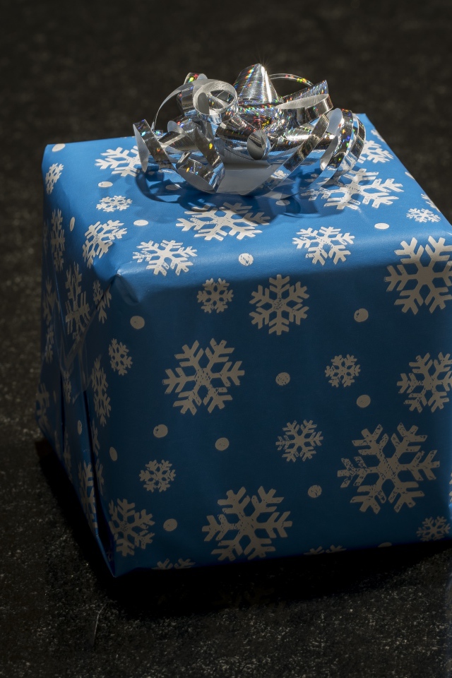 Большой голубой подарок с бантом на черном фоне 