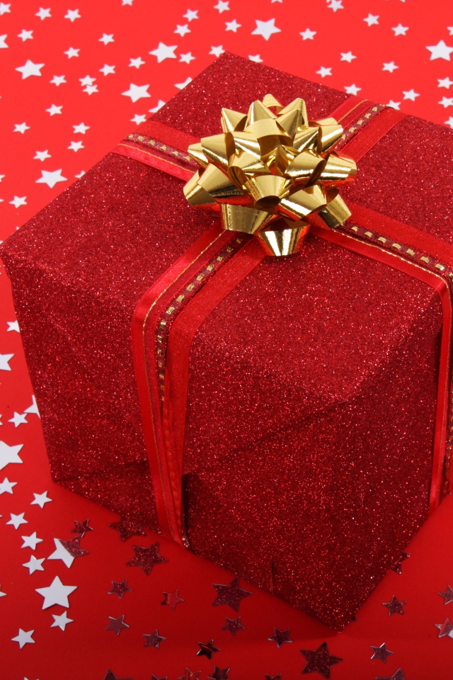 Большой подарок с бантом на красном фоне со звездами 