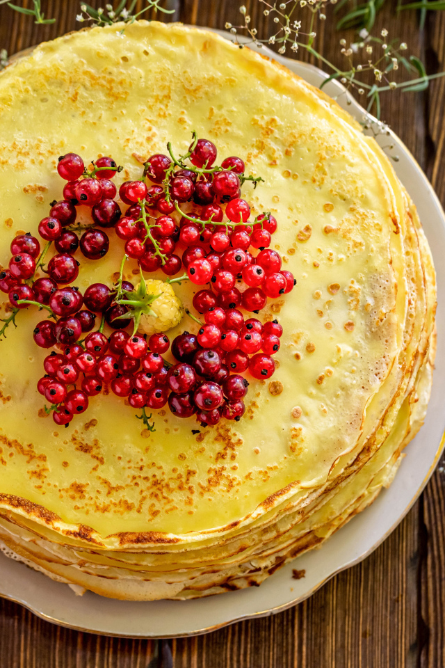 Аппетитные блины с ягодами красной смородины на столе 