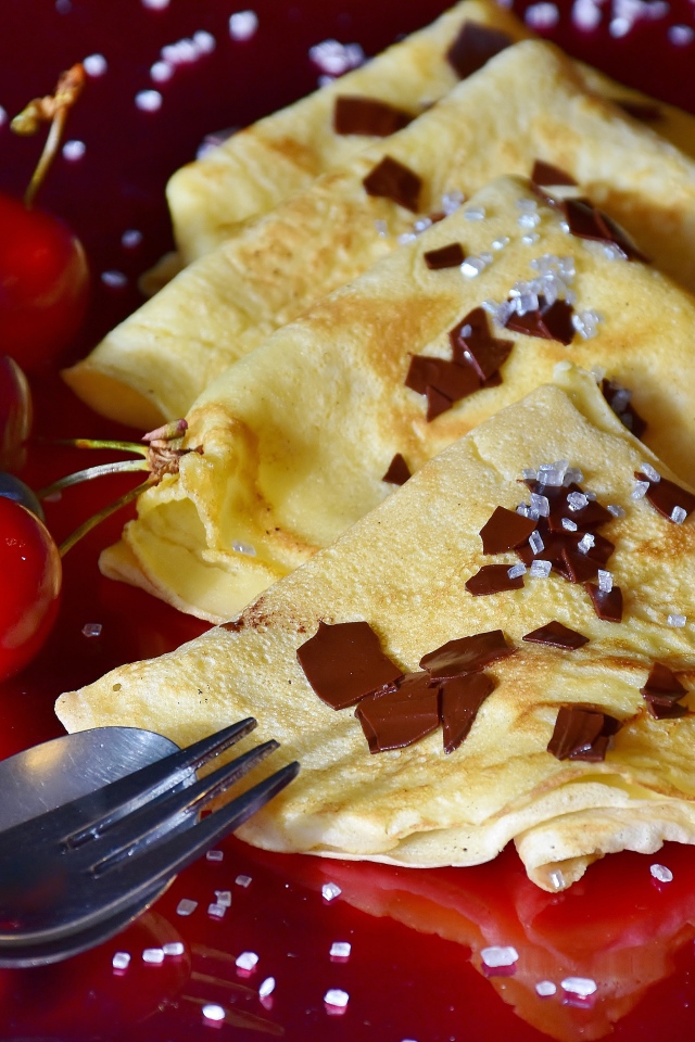 Тонкие блинчики с вишней и черникой на красном фоне масленице