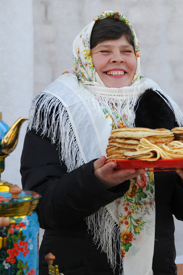 Женщина с блинами и самоваром на Масленицу