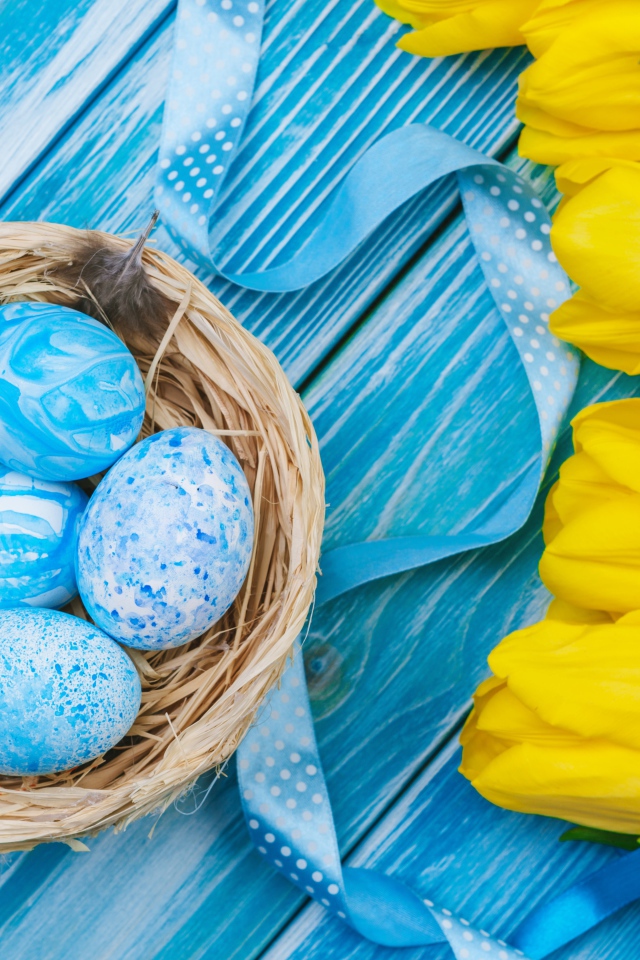 Крашеные яйца и букет желтых тюльпанов на голубом фоне на Пасху