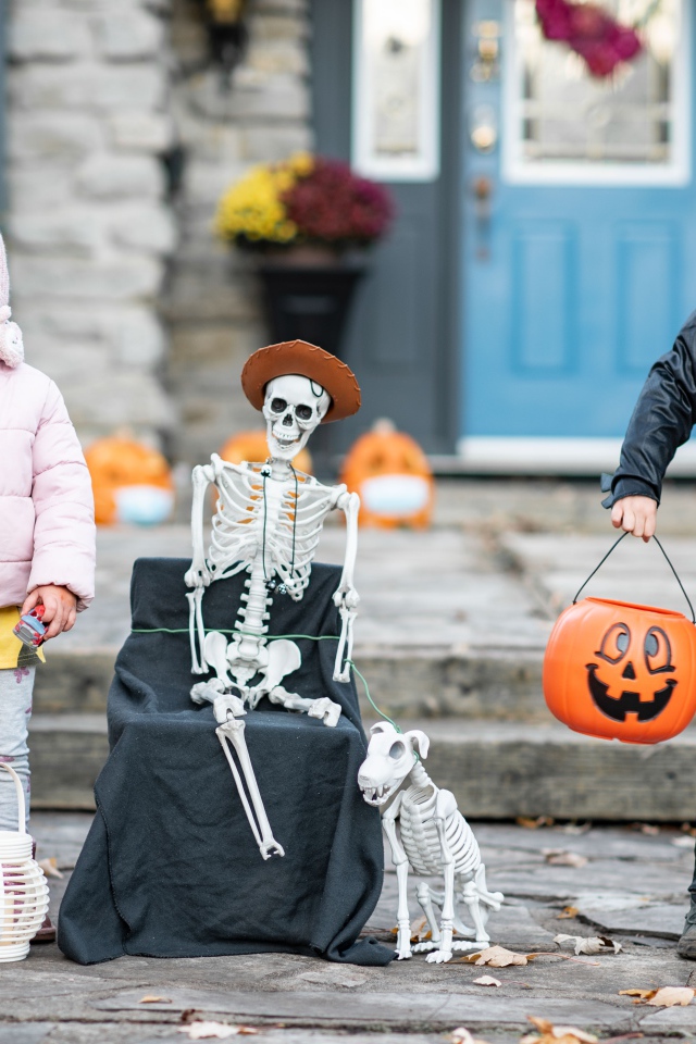 Маленькие дети со скелетом на праздник Хэллоуин