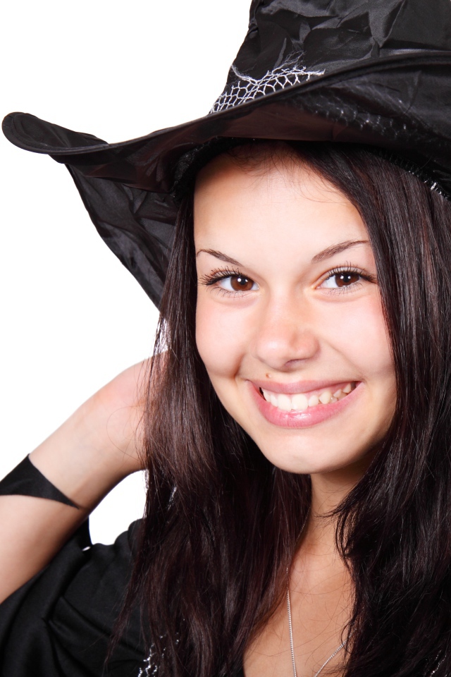 Улыбающаяся девушка в костюме ведьмы на Хэллоуин