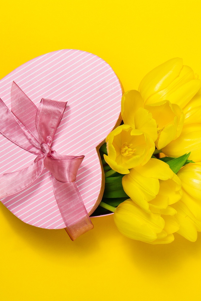 Подарок и букет тюльпанов на желтом фоне на Международный женский день