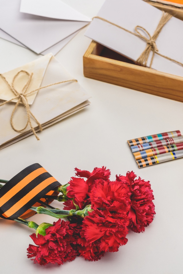 Букет красных гвоздик, ордена и часы на День победы 9 мая