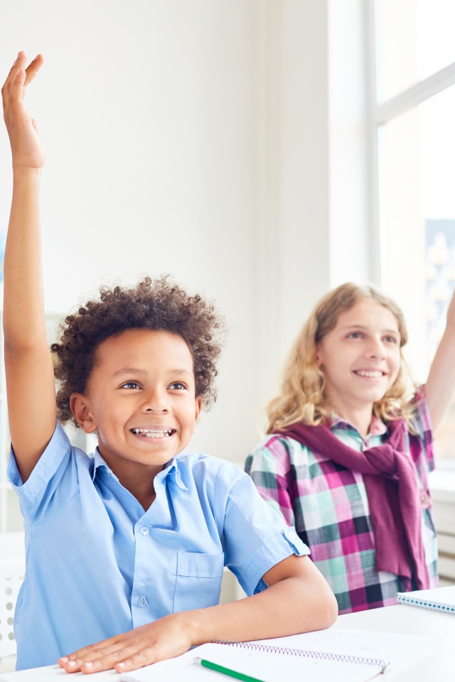 Дети школьники с поднятой  рукой в классе на 1 сентября 