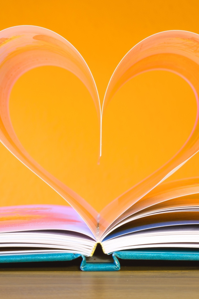 Сердце из страниц книги на оранжевом  фоне  