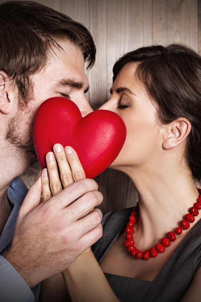 Поцелуй влюбленной пары за красным сердцем