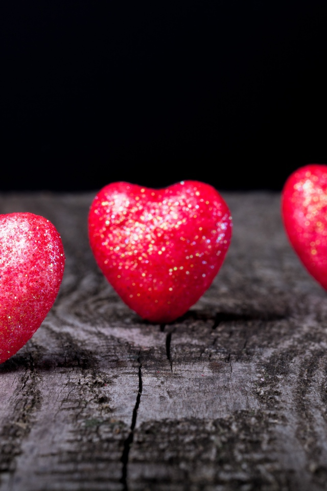 Блестящие красные сердечки на деревянном столе
