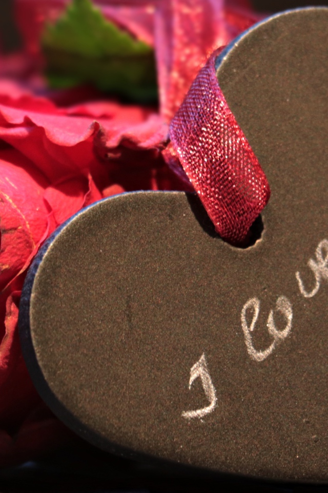 Каменное сердце с ленточкой на столе с розой 