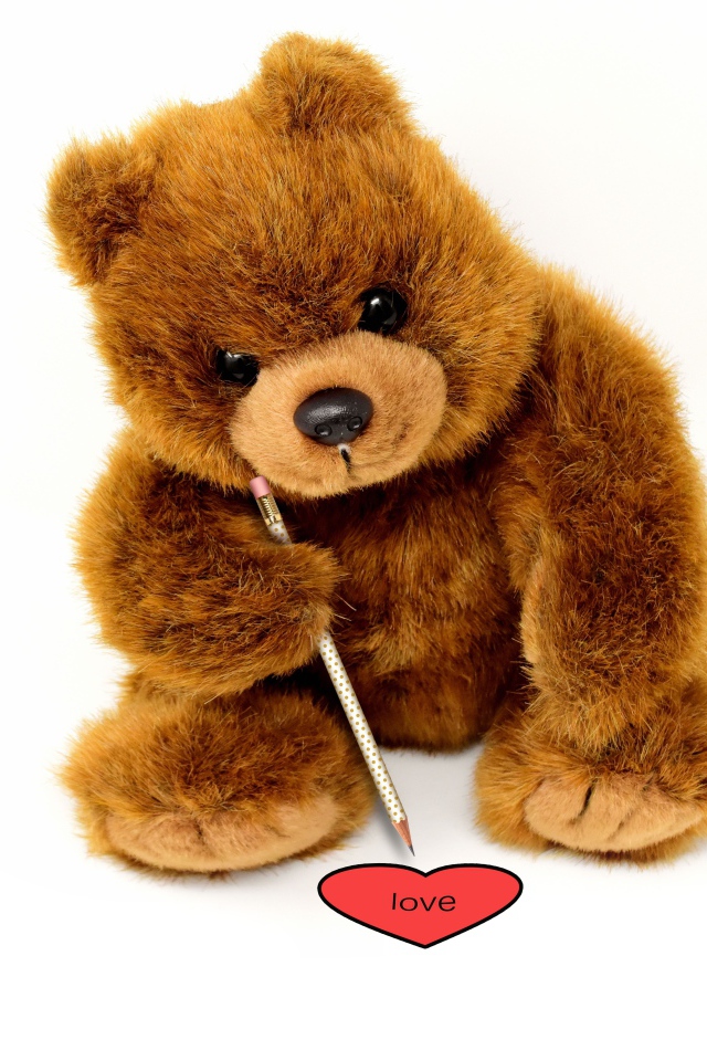 Toy teddy bear draws a heart on a white background