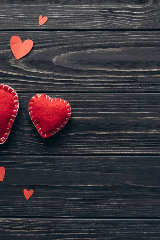 Два больших  красных сердца с маленькими  на деревянном столе 