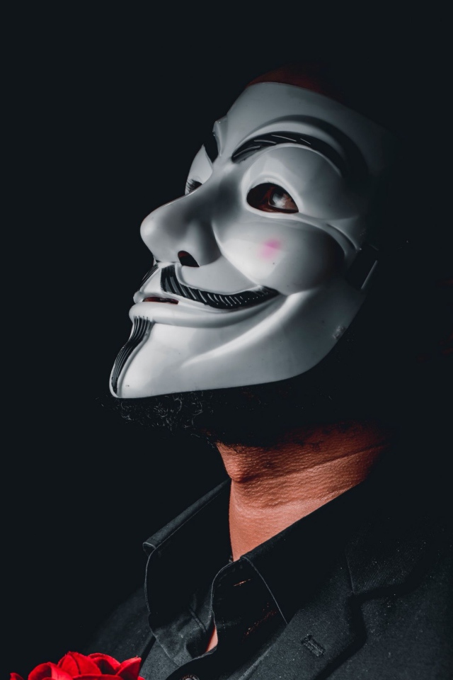 Мужчина в белой маске анонимуса на черном фоне 