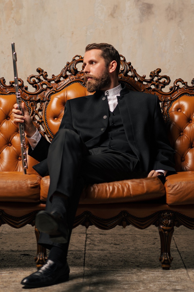 Солидный мужчина в костюме сидит на диване