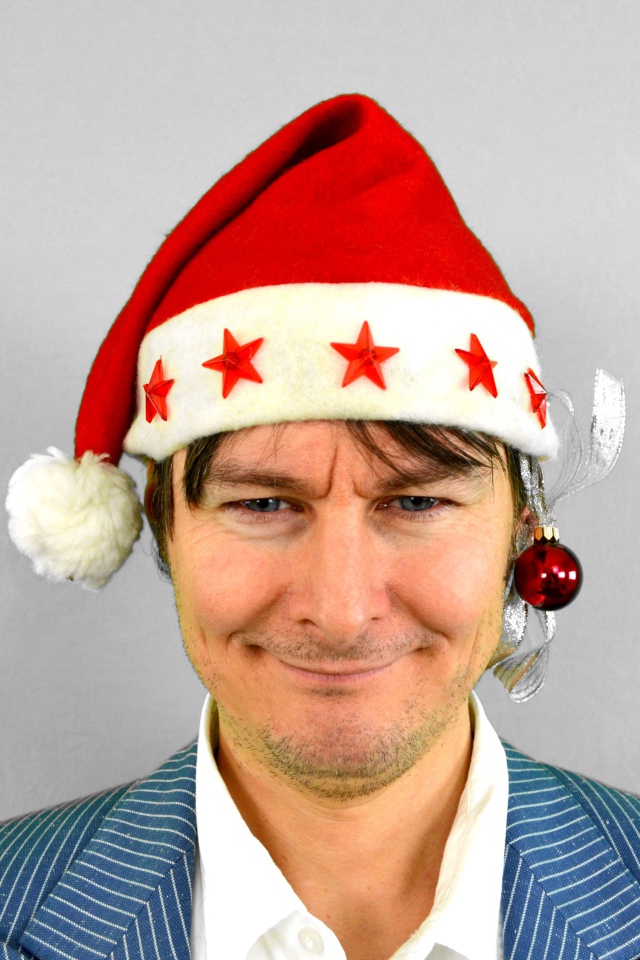 Голубоглазый мужчина в новогодней шапке на сером фоне 