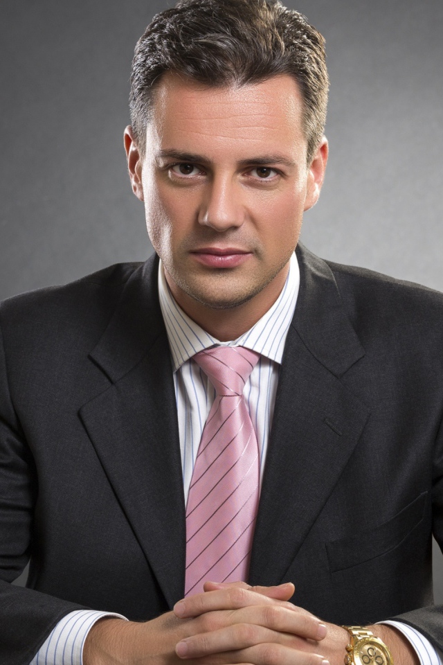 Деловой мужчина в костюме на фоне серой стены 