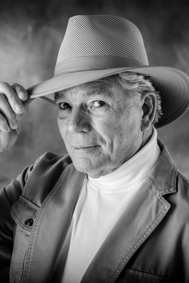 Пожилой мужчина в шляпе на фоне дыма 