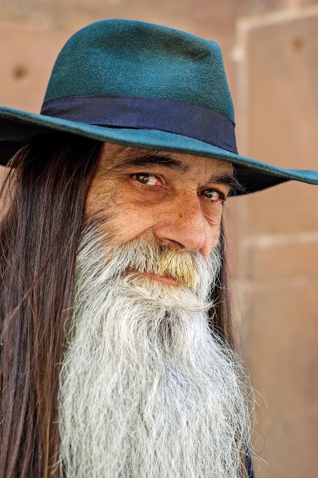 Пожилой мужчина с длинными волосами в шляпе 
