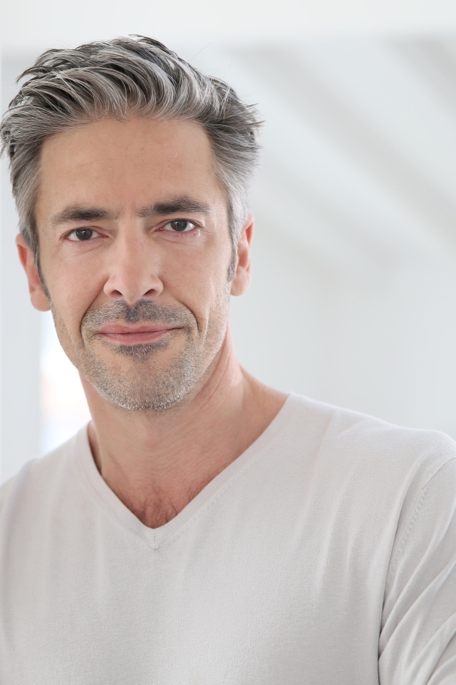 Седой стильный мужчина у стены