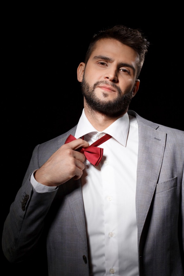 Красивый мужчина в сером пиджаке на черном фоне