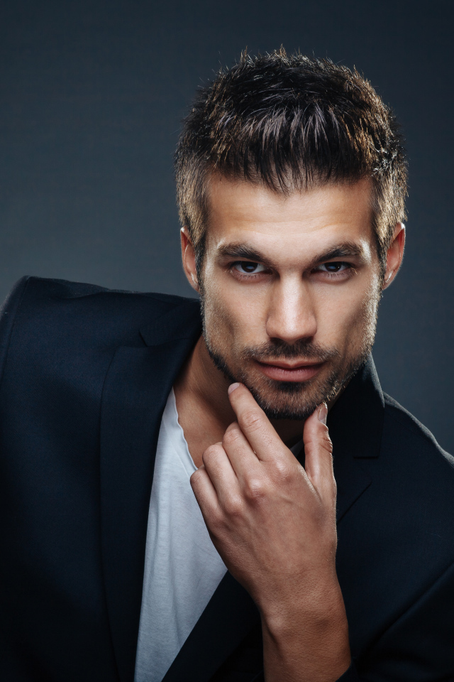 Красивый стильный мужчина в пиджаке на сером фоне 