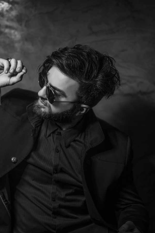 Мужчина в черном костюме на фоне стены