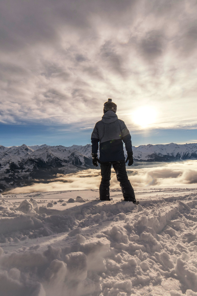 Человек в заснеженных горах в лучах солнца
