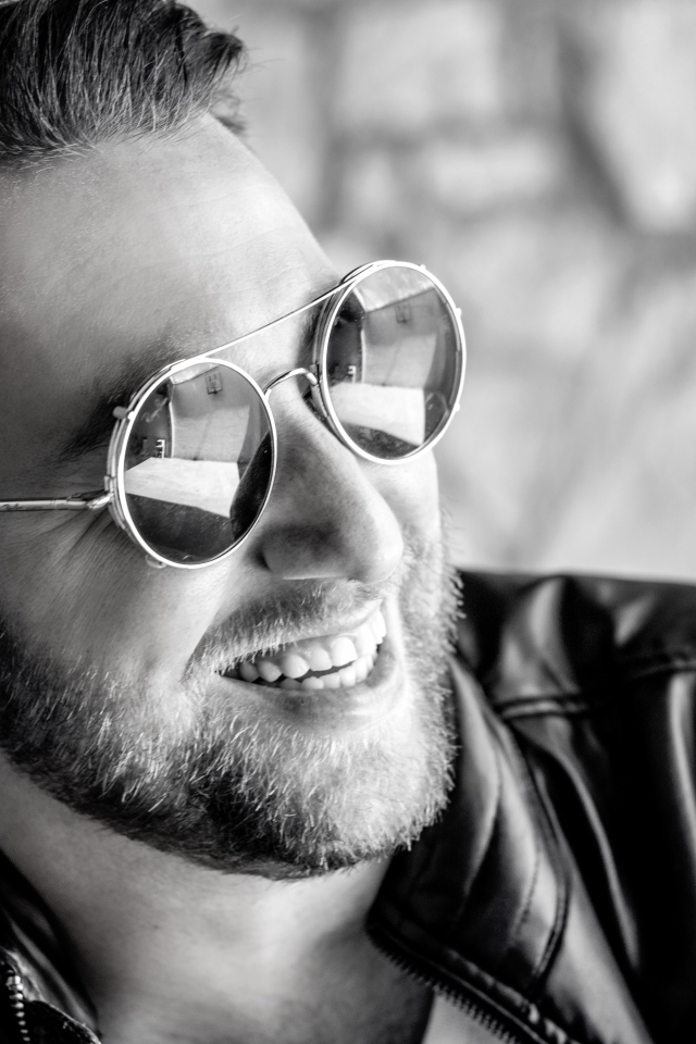 Улыбающийся брутальный мужчина в черных очках