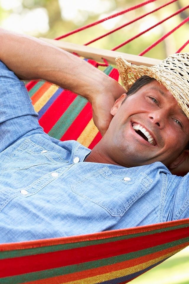 Улыбающийся мужчина спит в гамаке